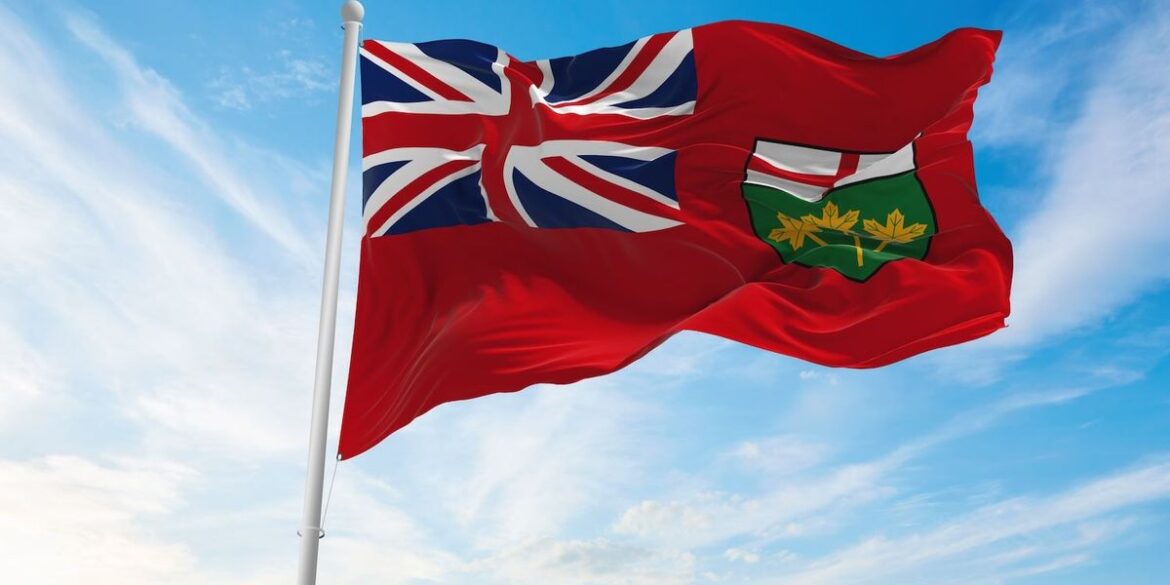 Ontario provincial flag waves against a blue sky.jpg