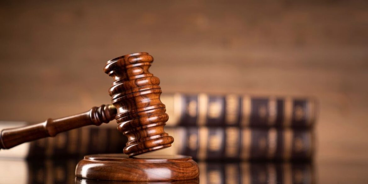 Wooden gavel on a reflective surface legal books blurred in the background.jpg