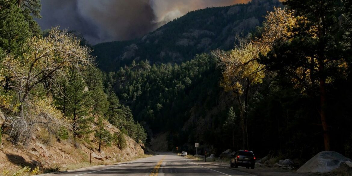 Road through forest with heavy smoke from distant wildfire in the mountains.jpg