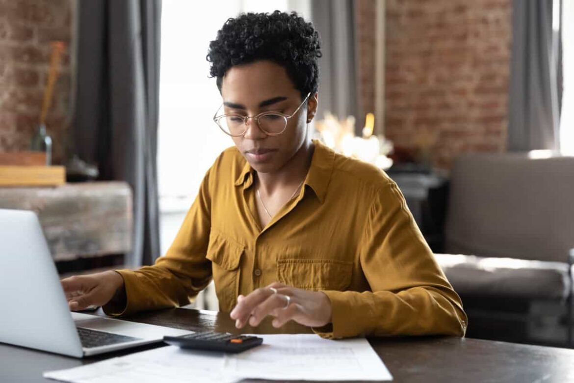 Focused millennial Black business woman calculating finance money using calculator laptop computer a.jpeg