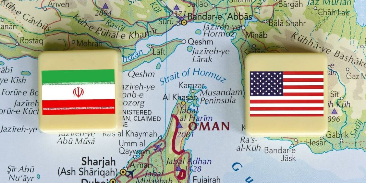 Two square blocks with the iranian and american flags are placed on a map of the strait of hormuz.jp .jpeg