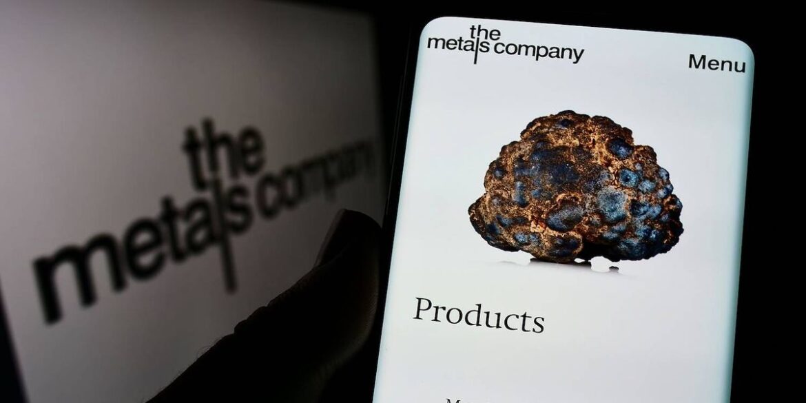 A smartphone displays a metallic nodule image and text while a blurred logo is in the background.jpg