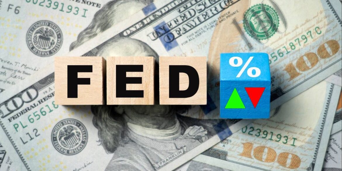 Wooden blocks spell fed next to a blue block with symbols on scattered us 100 bills.jpg