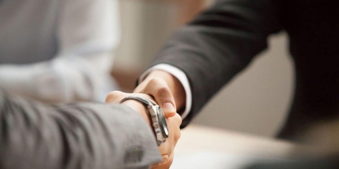 Two people in suits shake hands agreeing to a deal.jpg